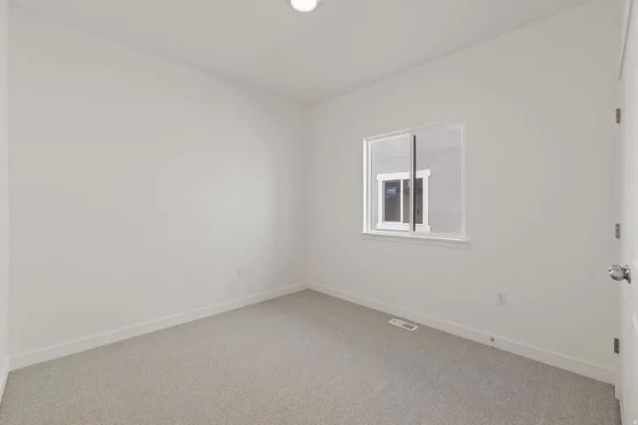 White walls, light-colored carpet, and a single window with white trim