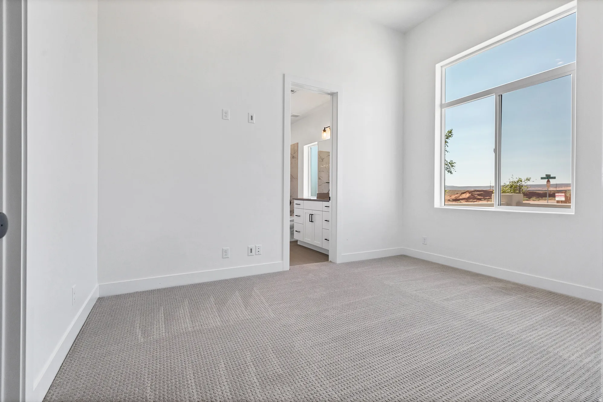 Light gray carpeting, a large window, and white walls