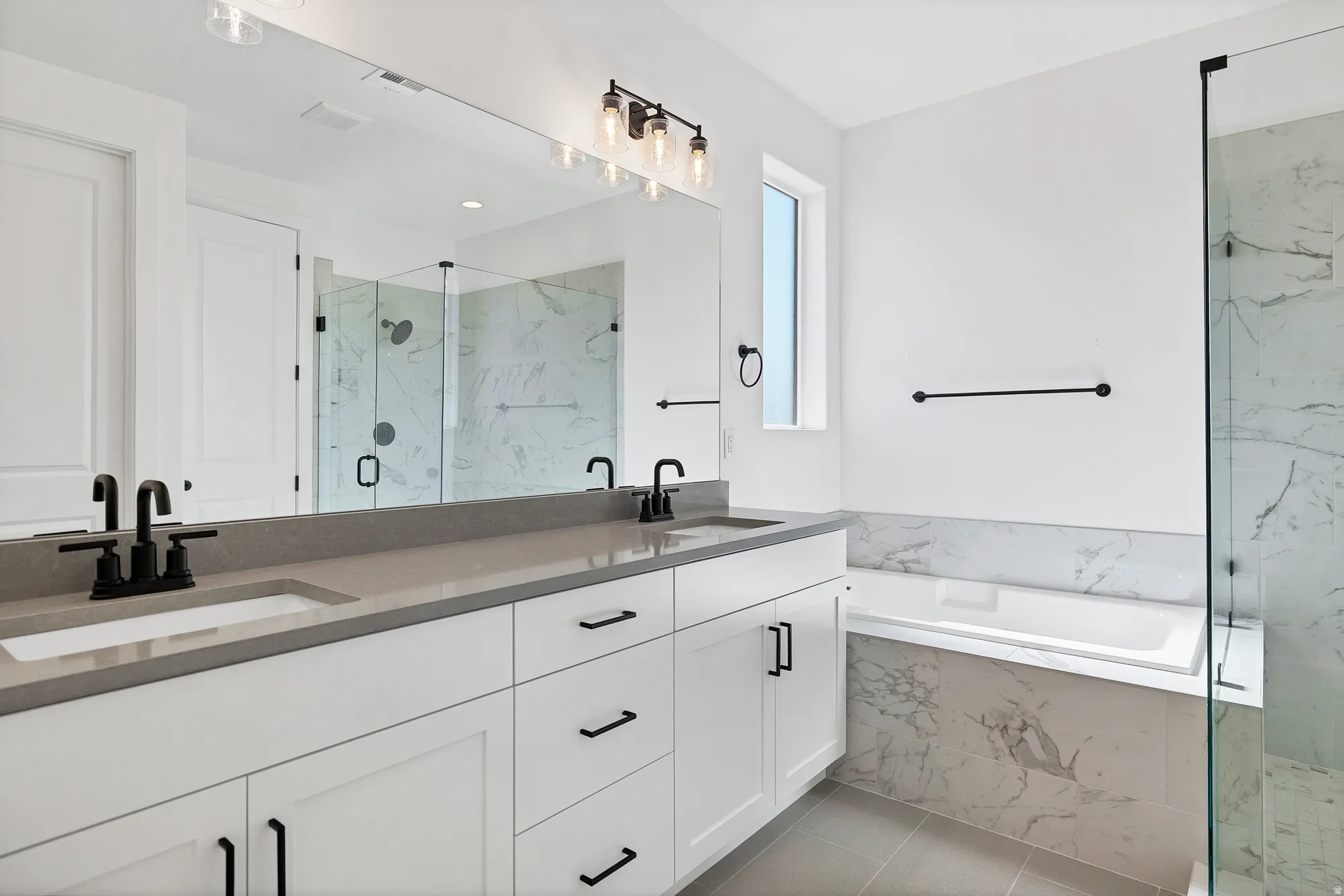 Dual vanity with undermount sinks, stone countertop, and matte black fixtures
