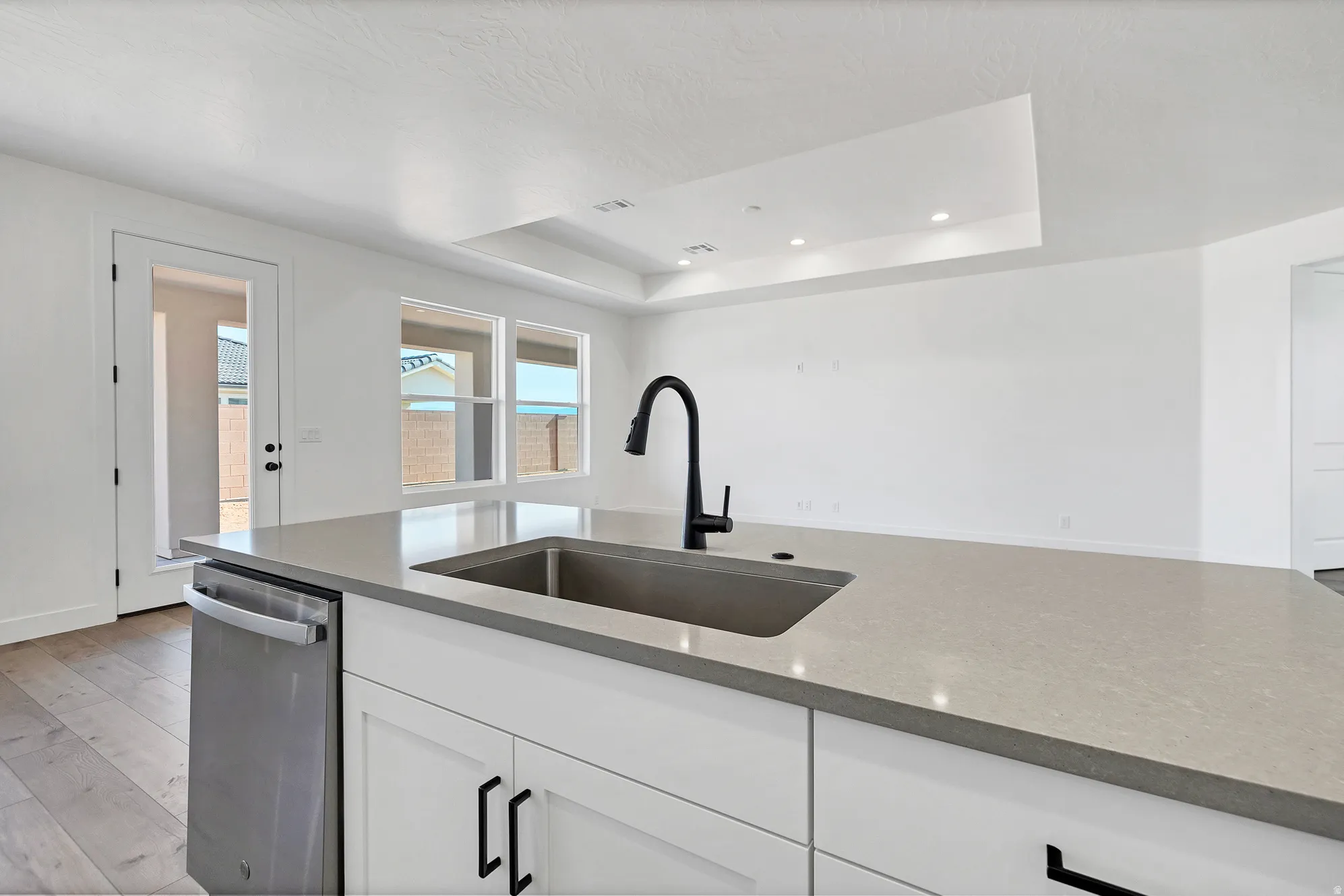 Kitchen island featuring a single-basin undermount sink, matte black faucet, and light-toned countertop