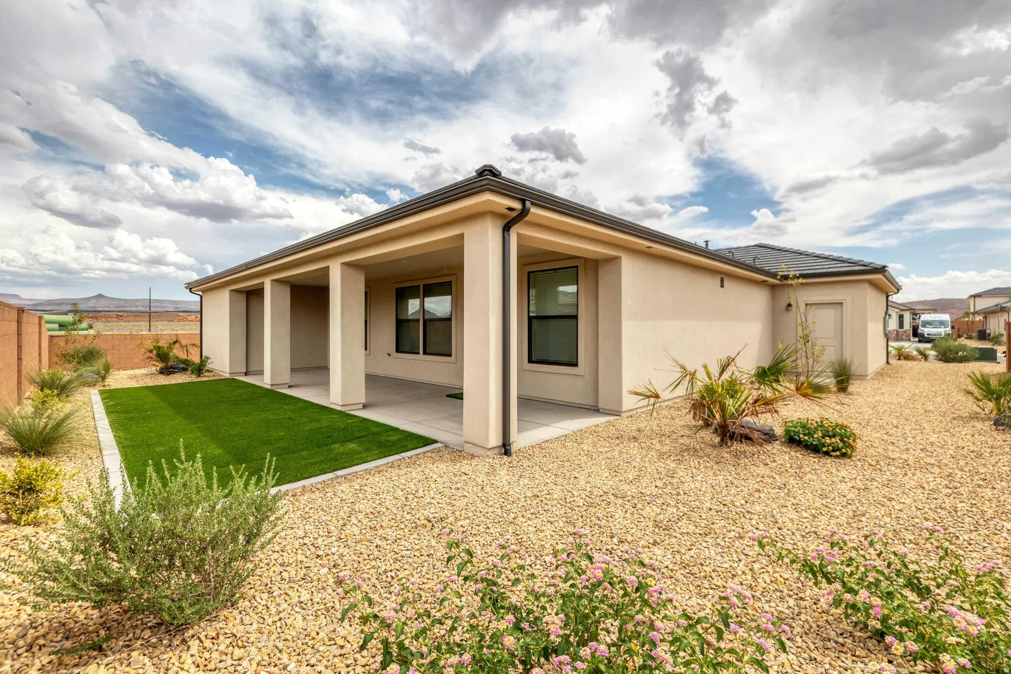 Covered patio with integrated artificial turf area, surrounded by low-maintenance gravel landscaping