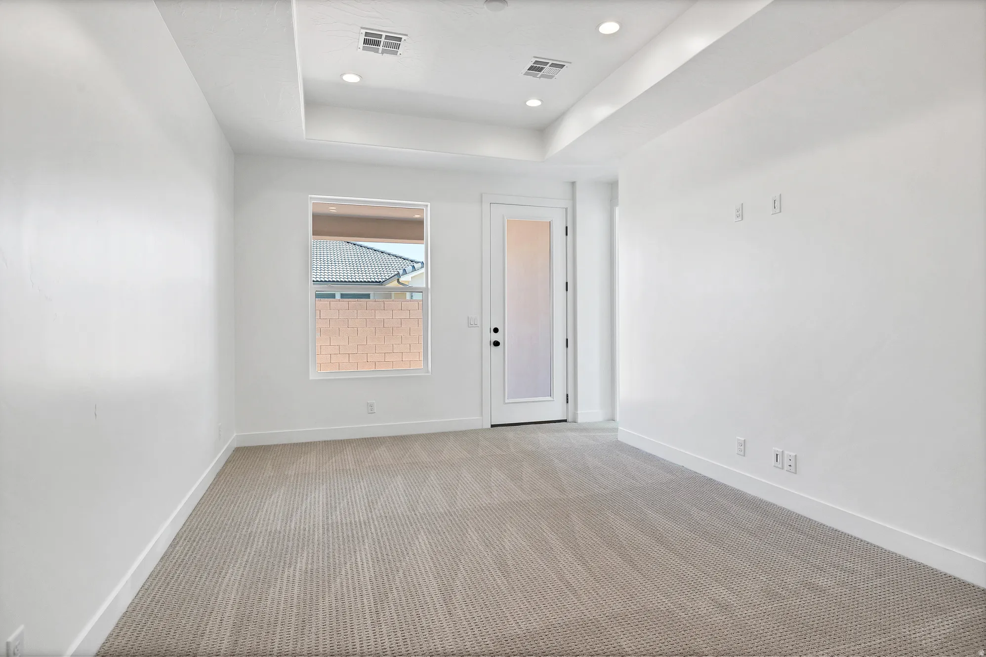 Recessed lighting, tray ceiling, carpeted flooring, window, and exterior access door