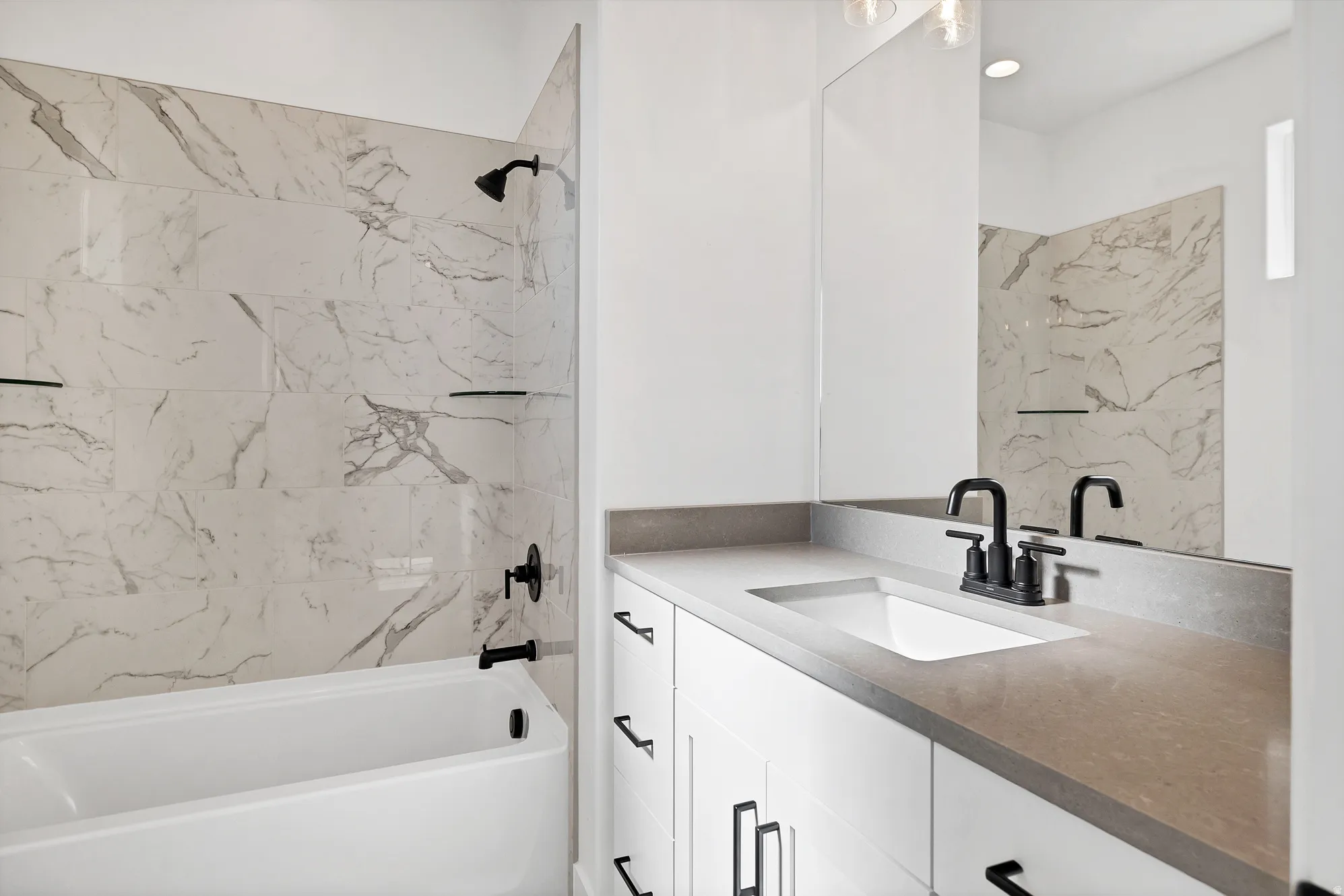 White vanity with integrated sink, a gray countertop, and black hardware