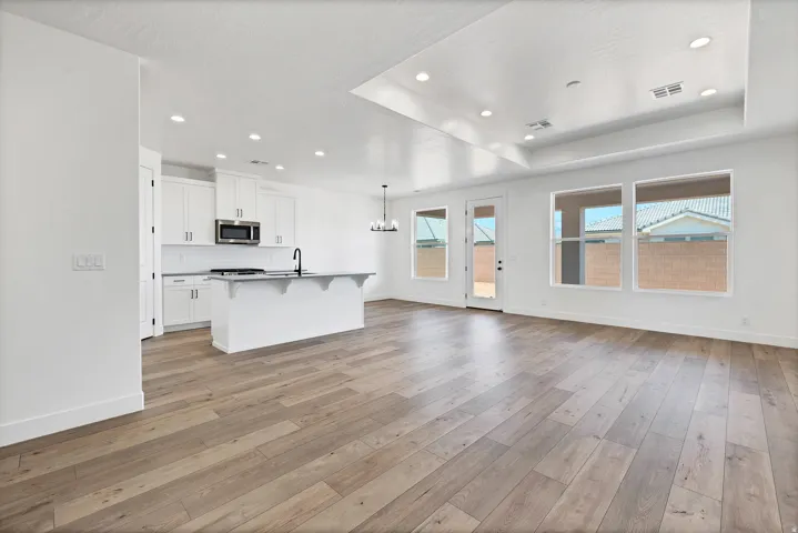 Open-concept living space with wood-finish flooring, recessed lighting, and a tray ceiling