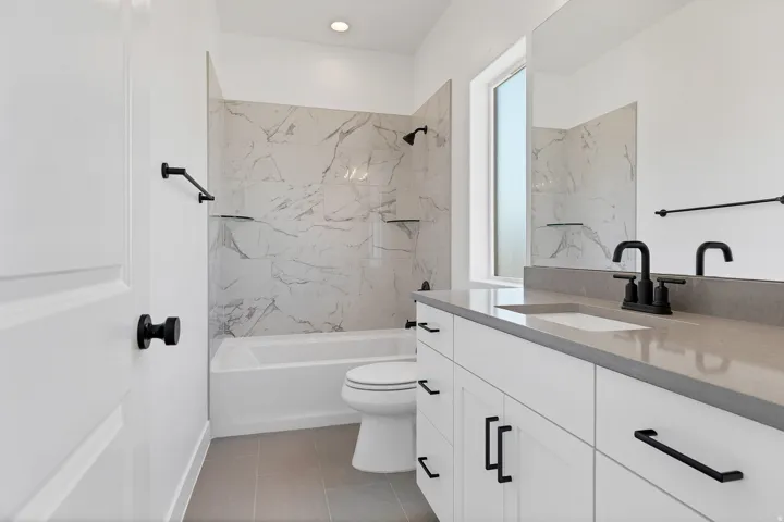 Full bathroom featuring a white vanity with a gray countertop, an integrated sink, and matte black fixtures