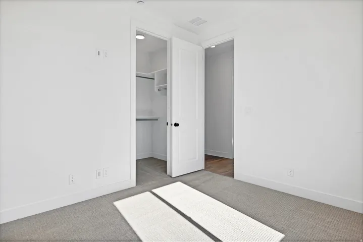 Plush carpet flooring, crisp white walls, and built-in closet shelving