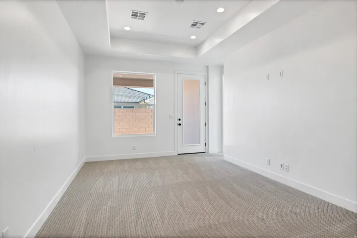 Recessed lighting, tray ceiling, carpeted flooring, window, and exterior access door