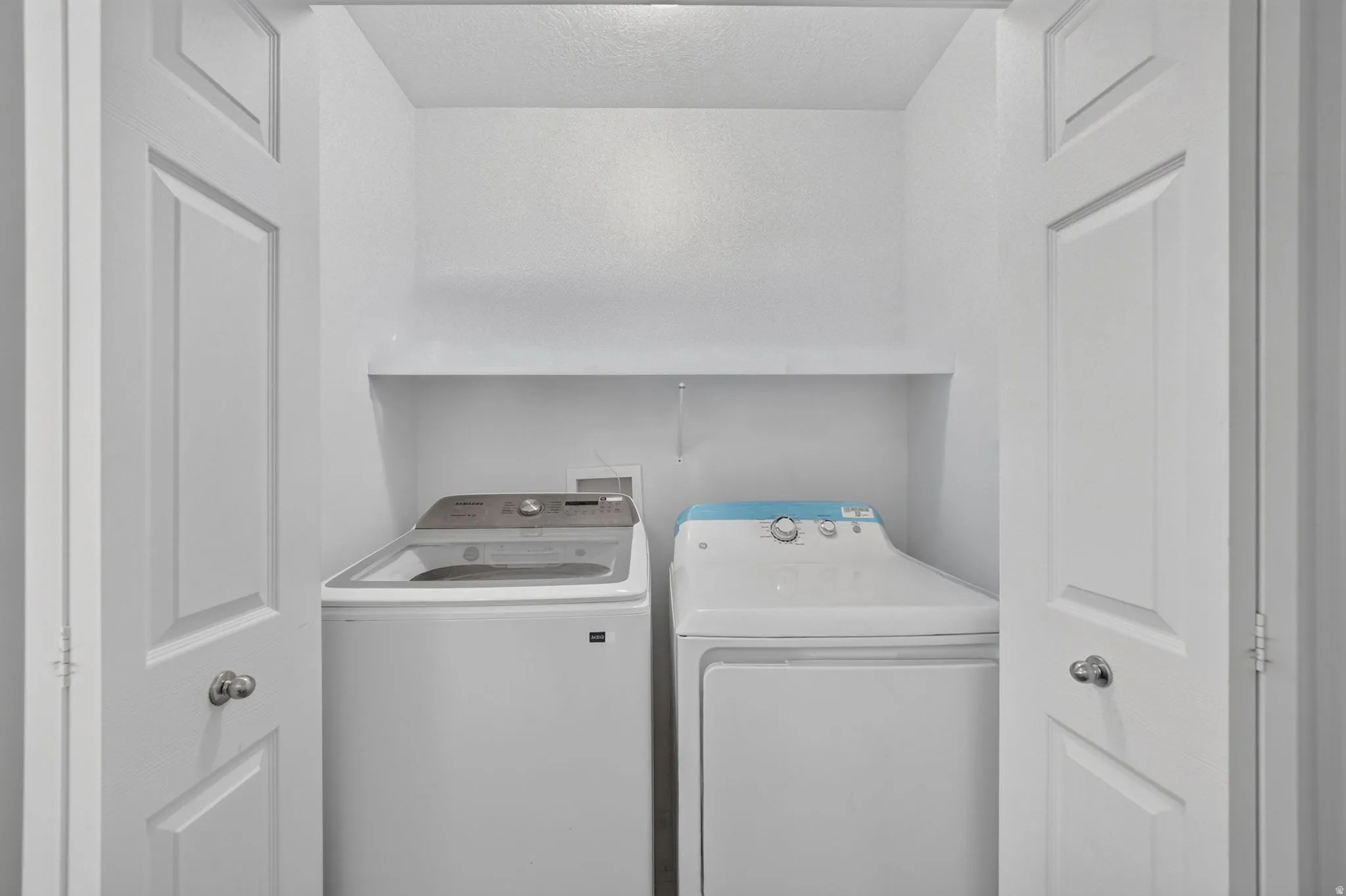 Laundry closet with bifold doors and an integrated storage shelf