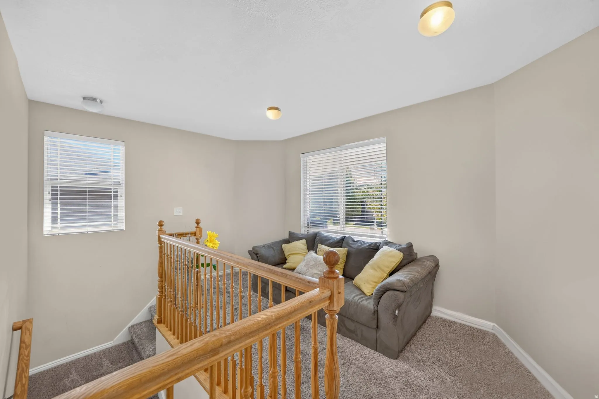 Bright upper-level landing featuring dual windows with plantation shutters, recessed lighting, and warm neutral walls