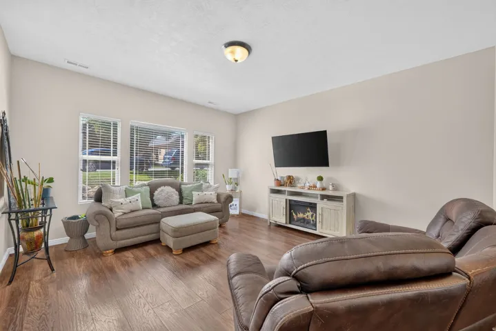 Living area featuring wood-finish flooring, multiple windows, a ceiling-mounted light fixture, and a built-in media console with an electric fireplace