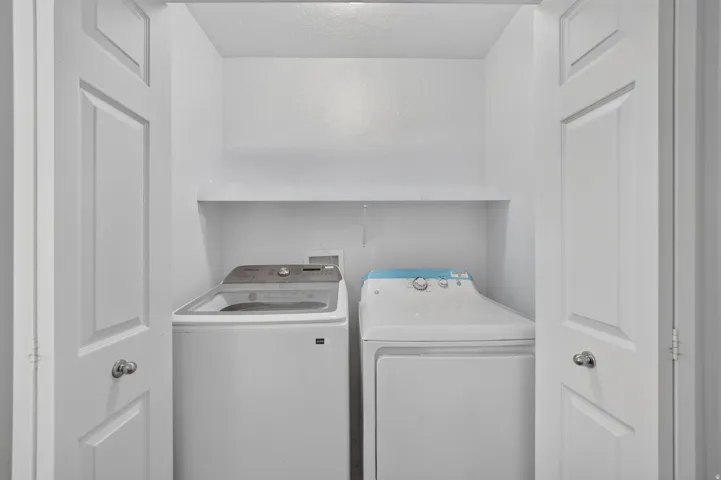 Laundry closet with bifold doors and an integrated storage shelf