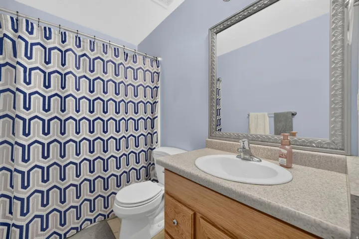 Built-in vanity with light-toned countertop, oval sink, and chrome faucet