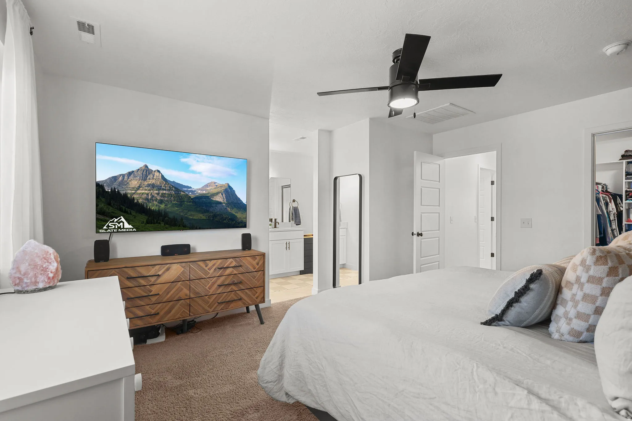 Carpeted room with a ceiling fan, white walls, and a built-in closet system