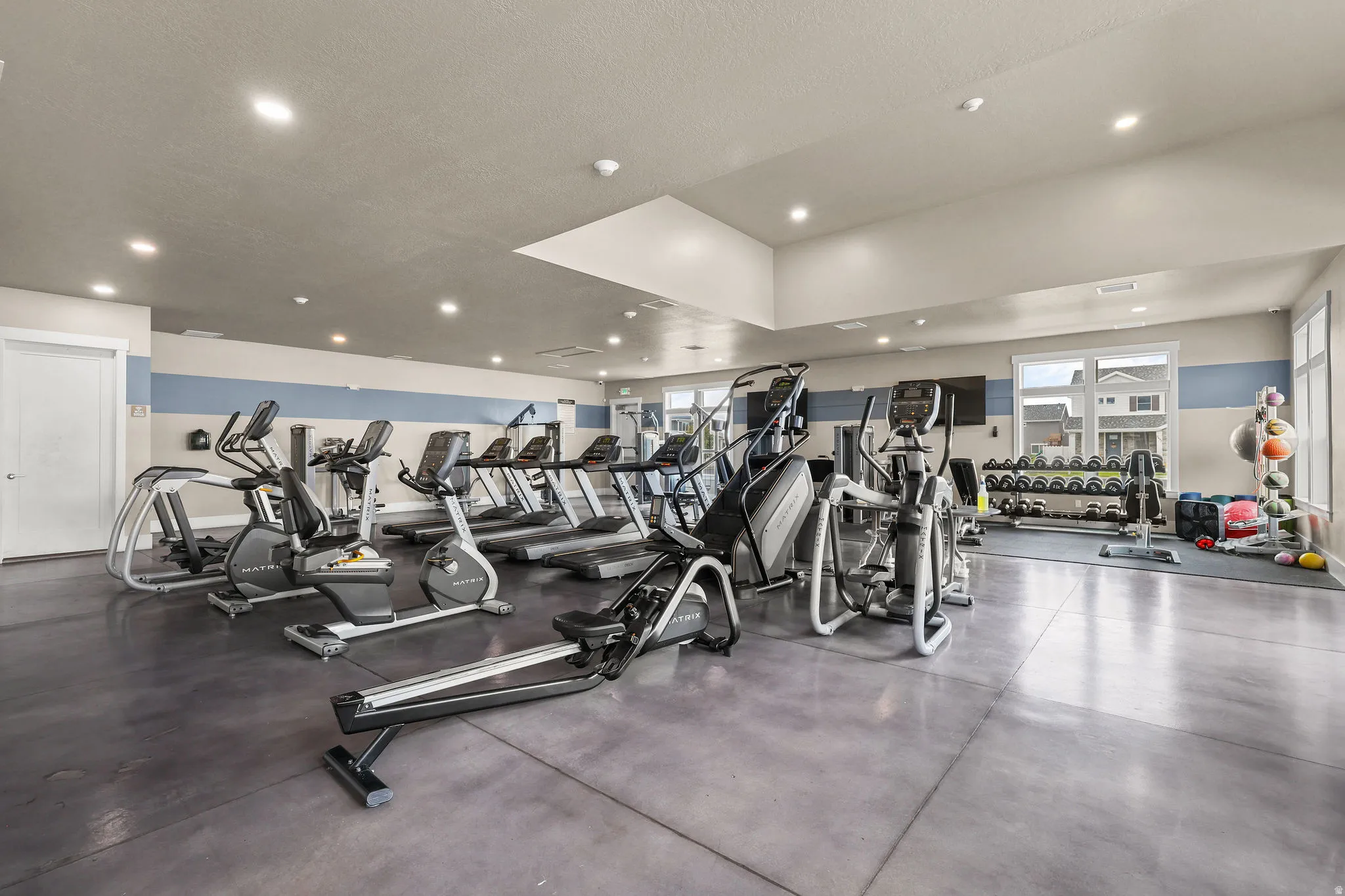 Gym space featuring recessed lighting, a variety of cardio equipment, strength training equipment, and large windows