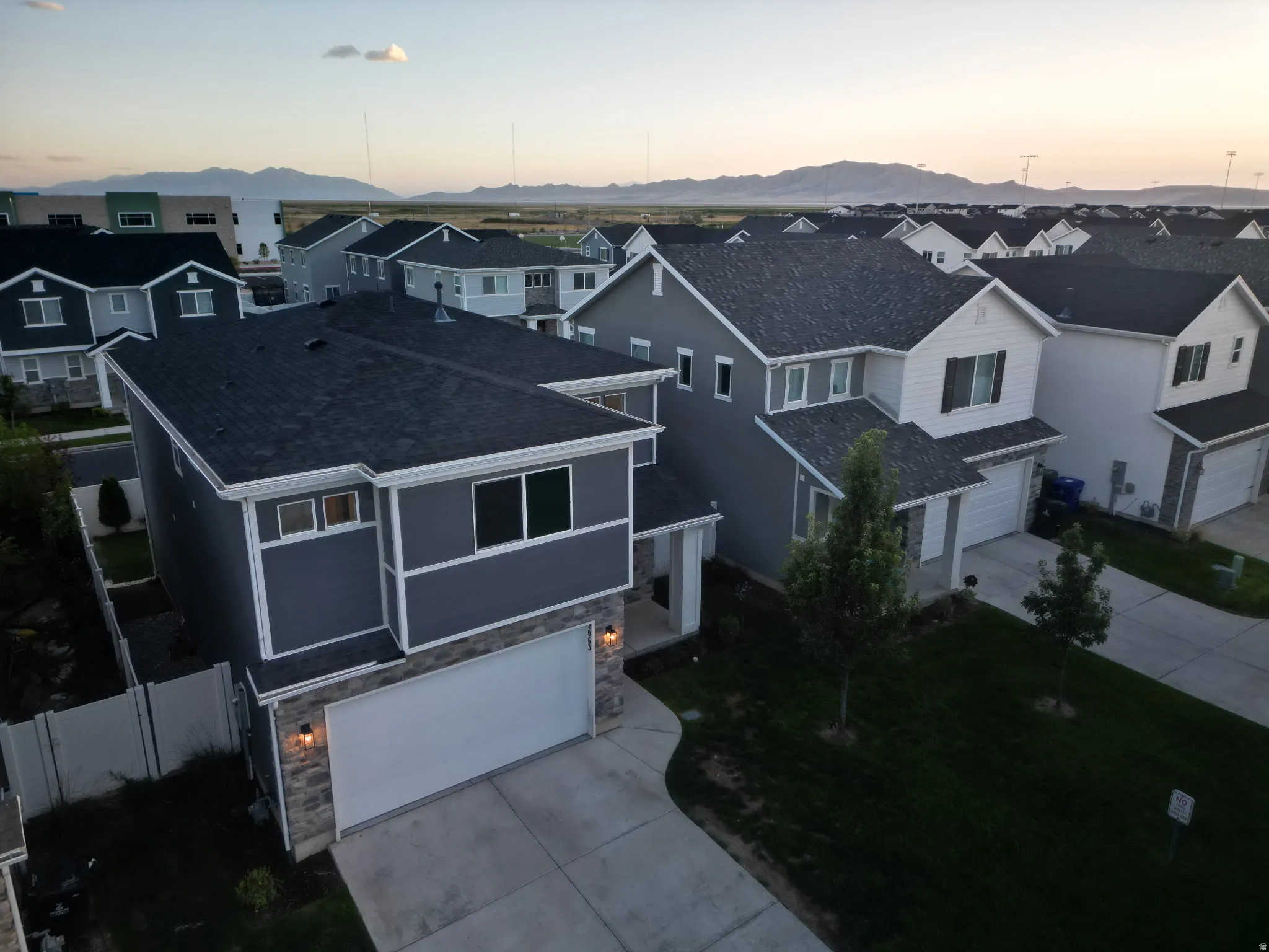 Contemporary exterior featuring a stone and siding facade, attached two-car garage, and established front yard landscaping