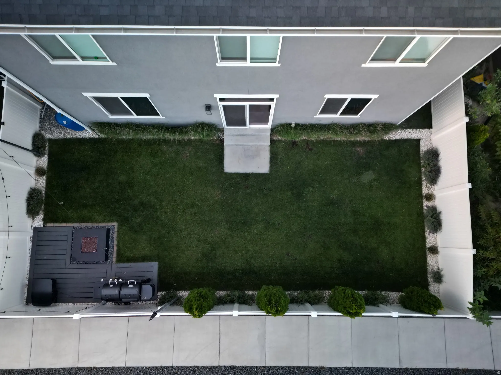 Enclosed backyard featuring a manicured lawn, an outdoor patio space, and perimeter landscaping