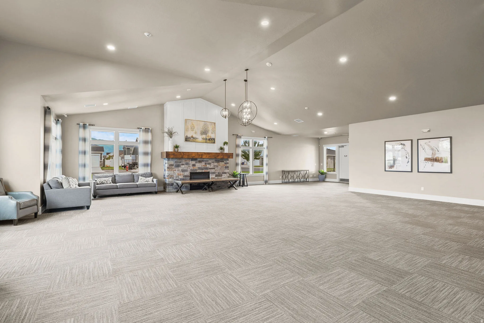 Vaulted ceilings with recessed lighting, stone-clad fireplace with wood mantel, large windows, and patterned carpet flooring