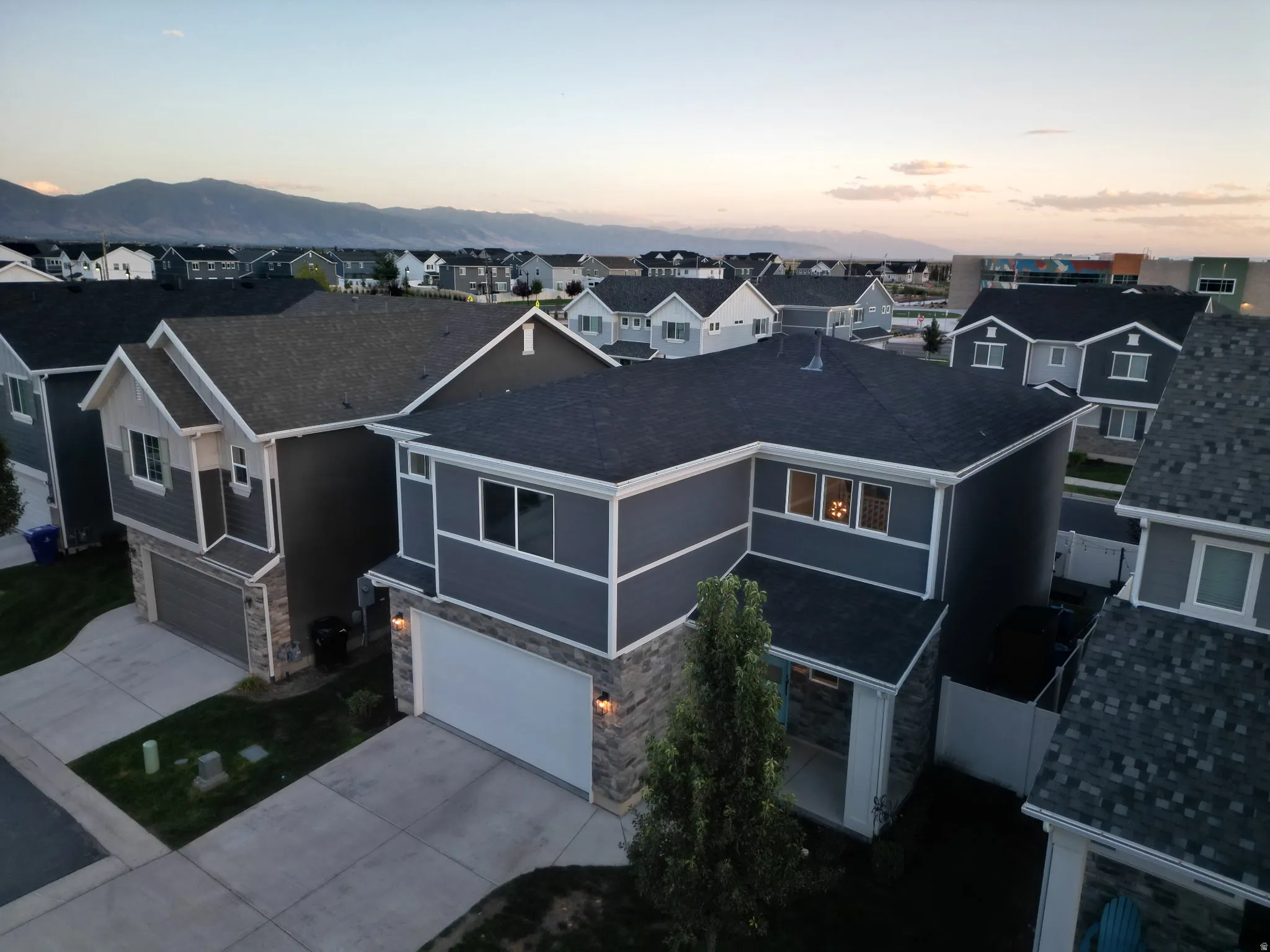 Two-story residence with dark gray siding, stone accent facade, and a two-car garage