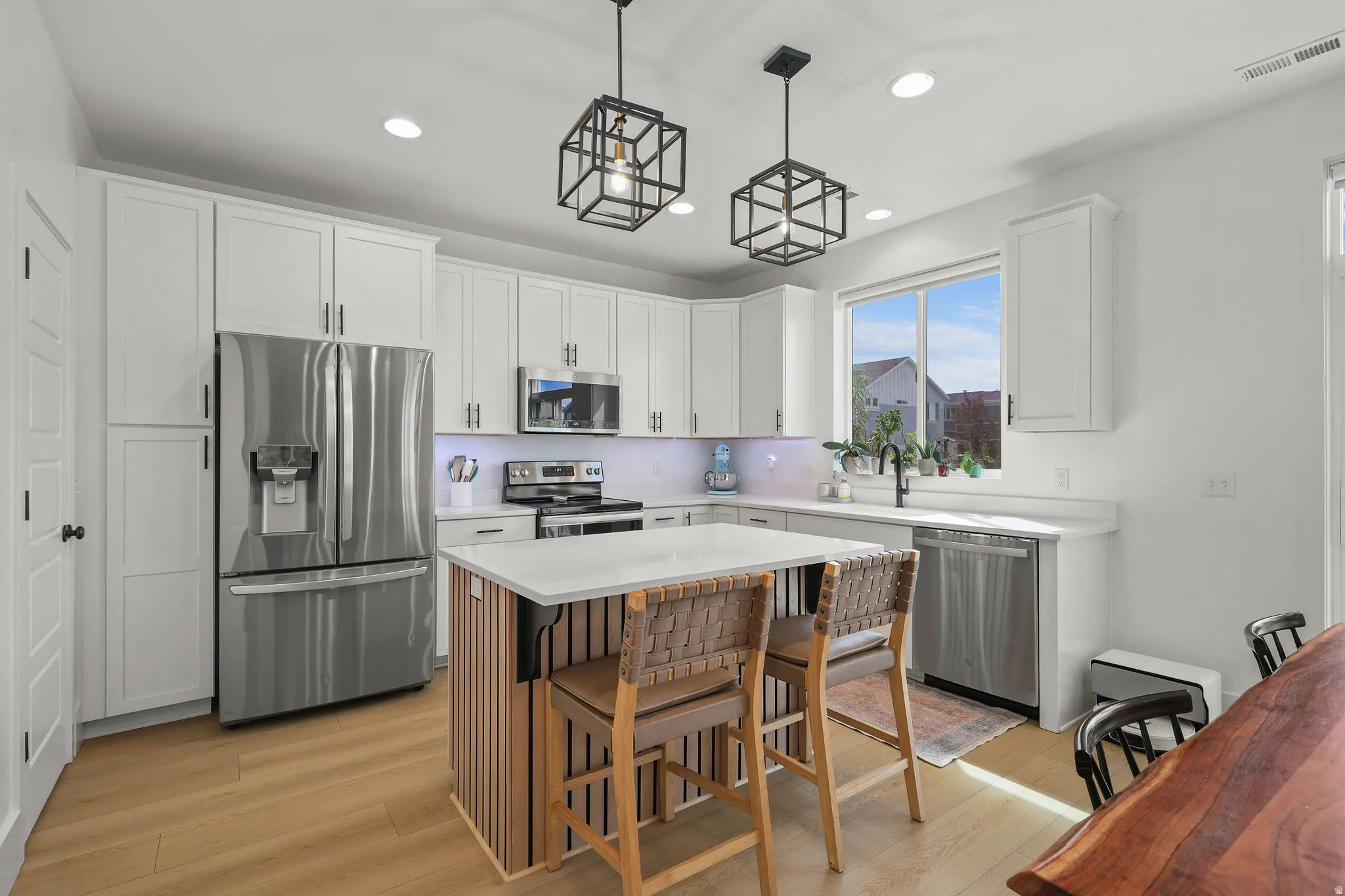 Modern kitchen featuring white cabinetry, stainless steel appliances, a center island with bar seating, and wood-finish flooring