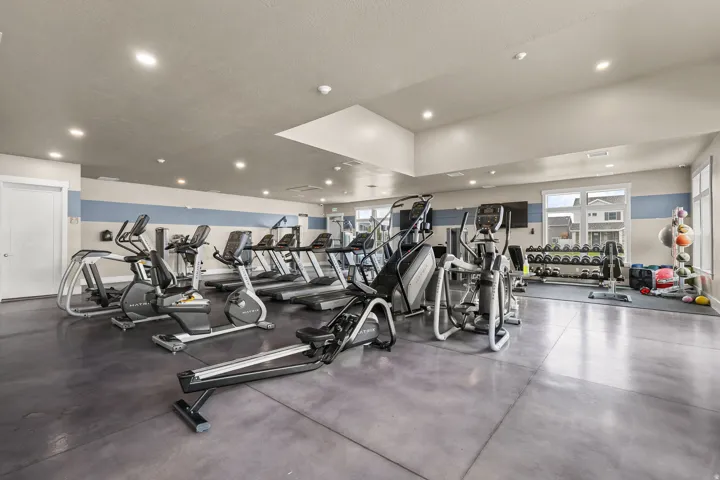 Gym space featuring recessed lighting, a variety of cardio equipment, strength training equipment, and large windows