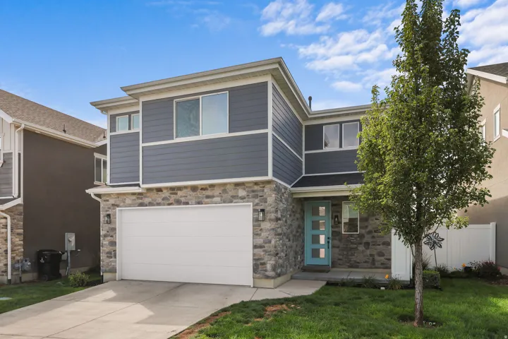 Exterior features a stone facade, horizontal siding, attached garage, and a light blue entry door with frosted glass inserts