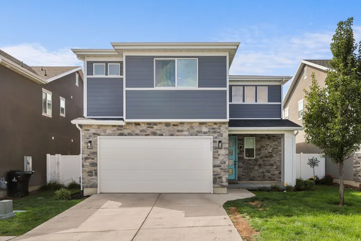 Modern two-story home featuring a striking facade of stone and board-and-batten siding, complemented by clean-lined architectural detailing