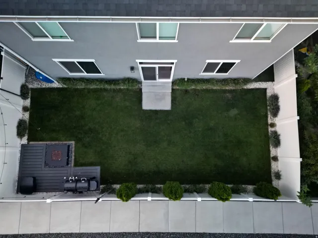 Enclosed backyard featuring a manicured lawn, an outdoor patio space, and perimeter landscaping