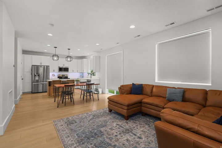 Open-concept living area featuring wood-finish flooring, recessed lighting, and roller shade window treatments