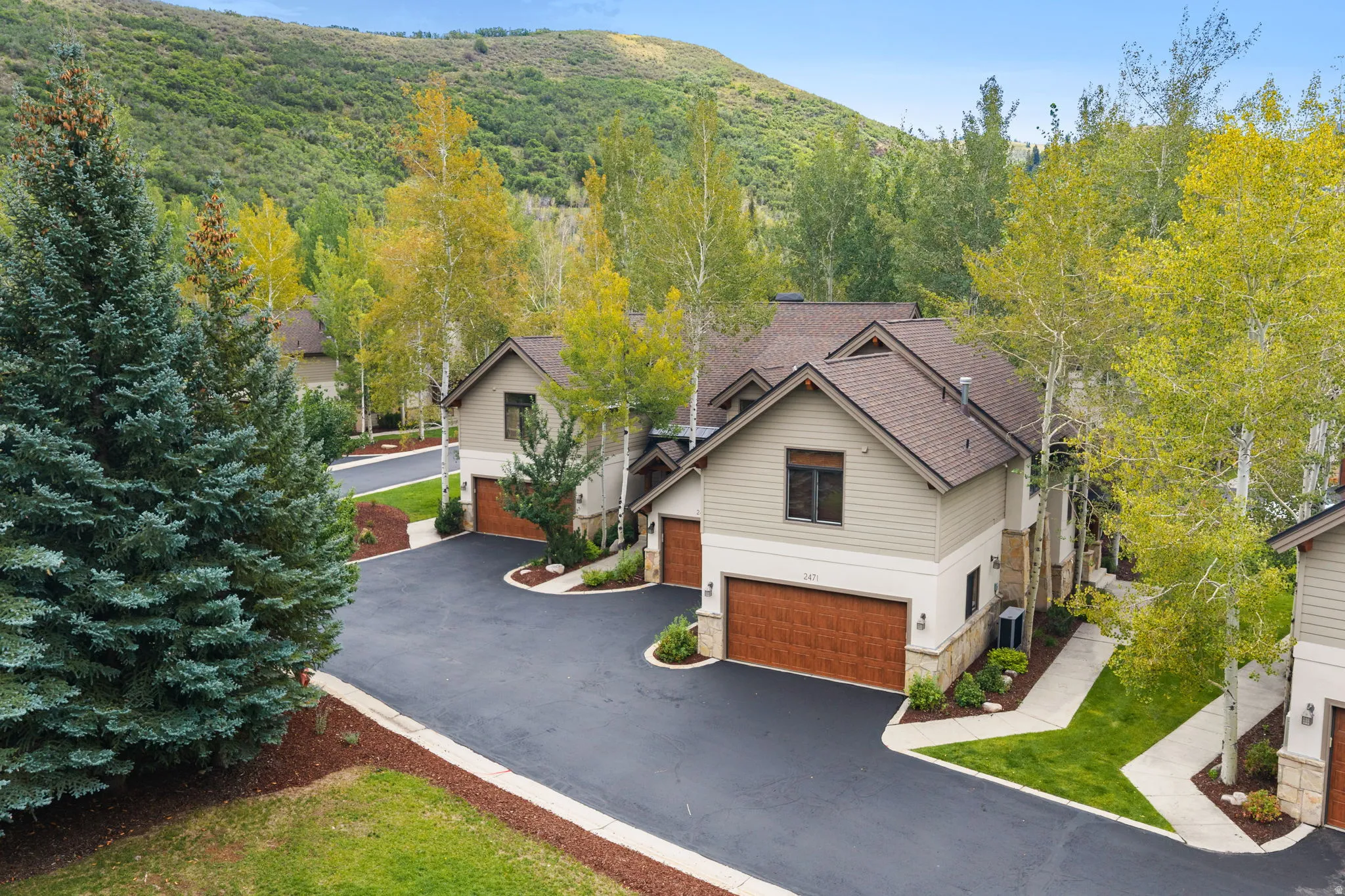 Contemporary exterior with a multi-gabled roofline, stone and siding finishes, and integrated garage doors