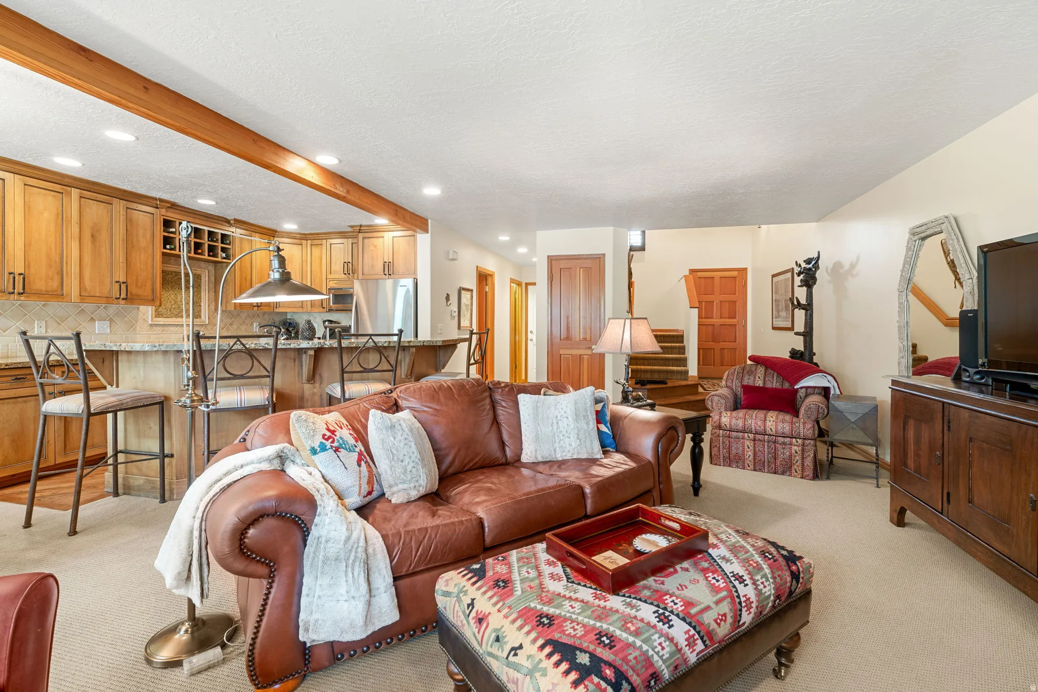 Open concept living area featuring natural wood cabinetry, stainless steel appliances, a breakfast bar with seating, and recessed lighting