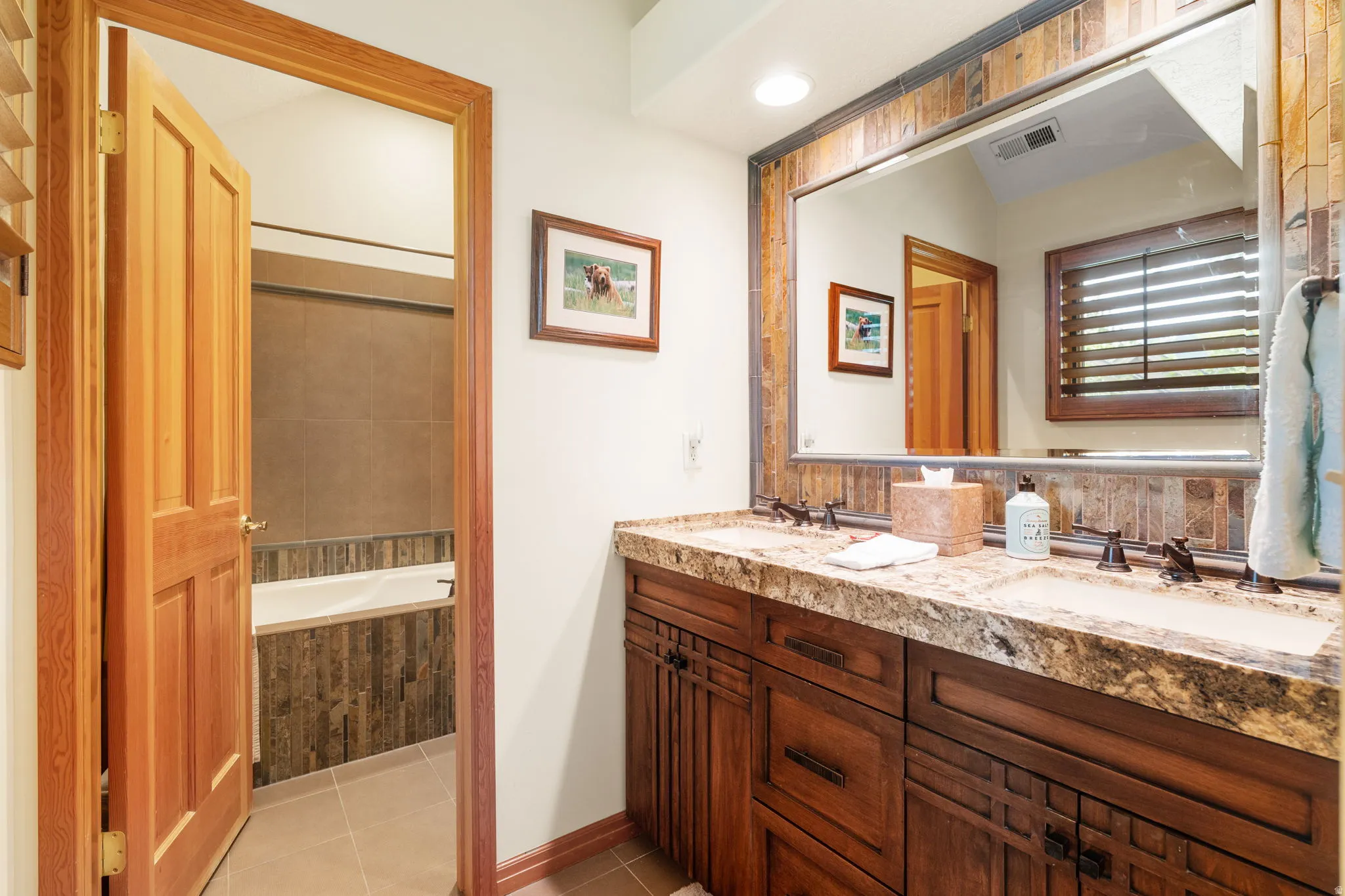 Dual vanity with integrated sinks, a stone-finish countertop, and dark wood cabinetry