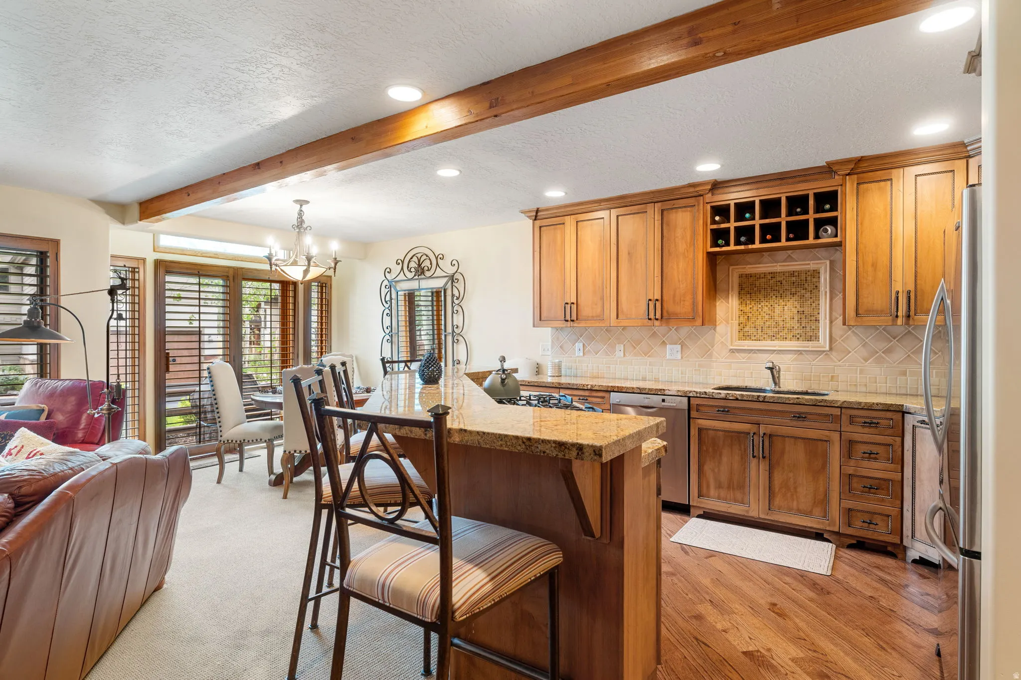 Kitchen featuring wood cabinetry, stainless steel appliances, a tile backsplash, and an island with a stone countertop