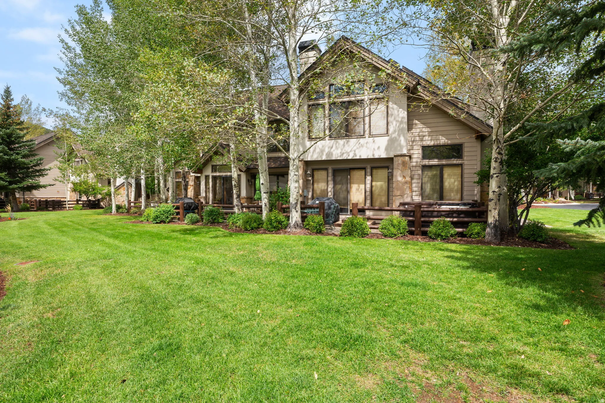 Expansive green lawn with mature deciduous and evergreen trees