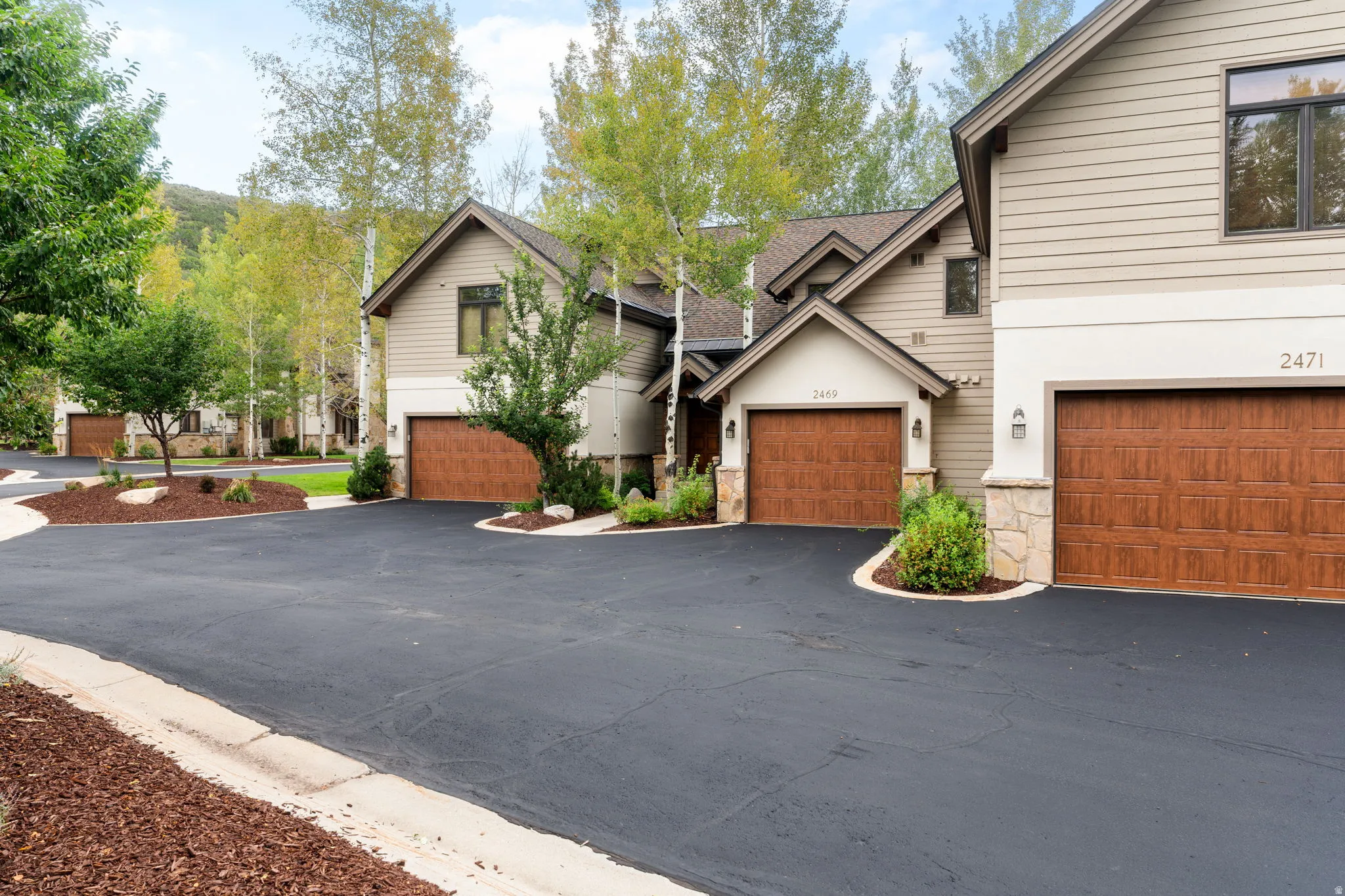 Contemporary-style residential structures featuring light-toned siding and stone accents
