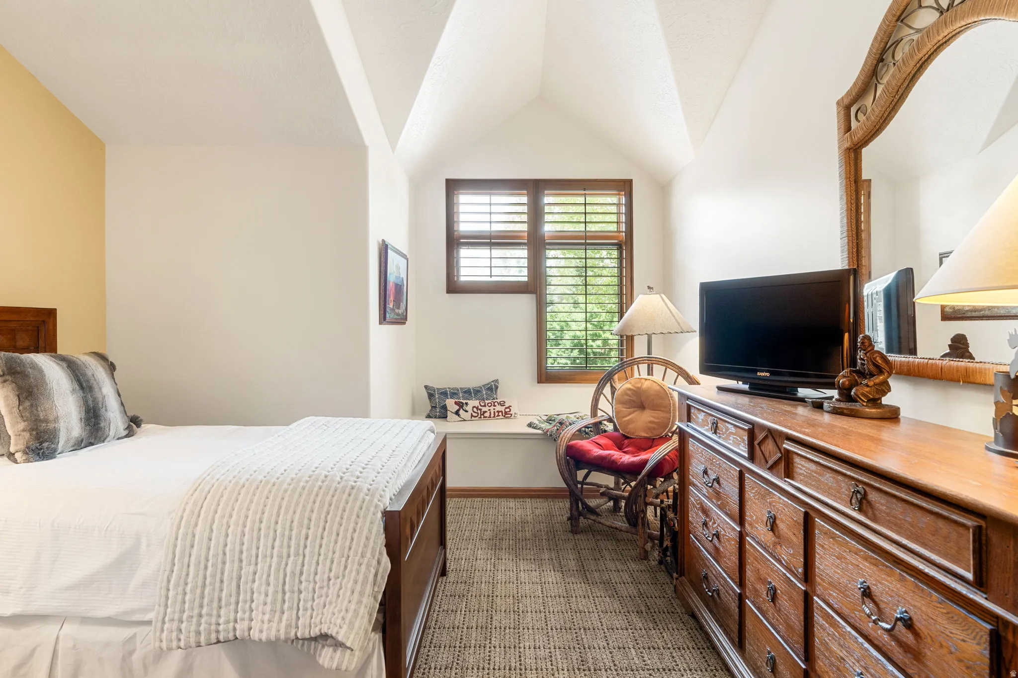 Vaulted ceilings with a window dormer, window shutters, and wood-finish flooring