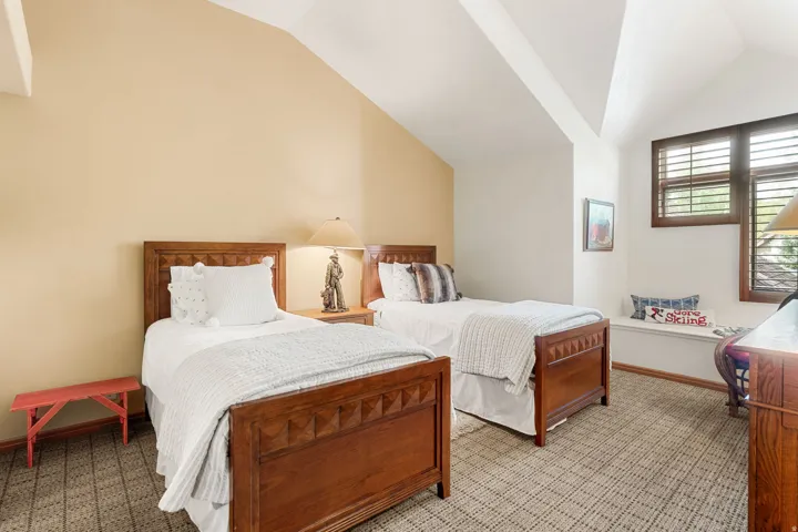 Sloped ceilings, patterned carpet flooring, built-in window seat, and wood-finish window shutters