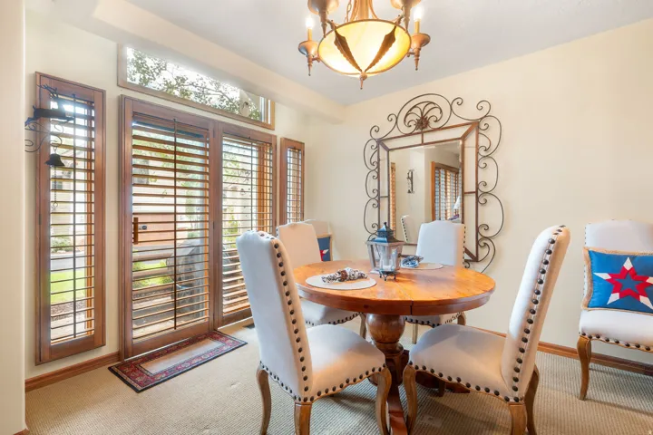 Sliding glass doors with wood-finish plantation shutters, transom windows, and a decorative chandelier