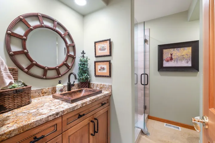Built-in vanity with a stone countertop, an undermount sink, and a dark-finished faucet