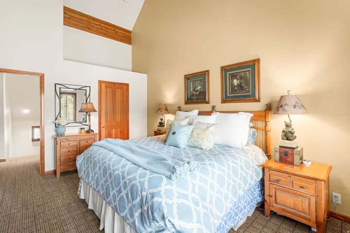 Vaulted ceiling with exposed wood beam, wood-finish flooring, and natural wood doors