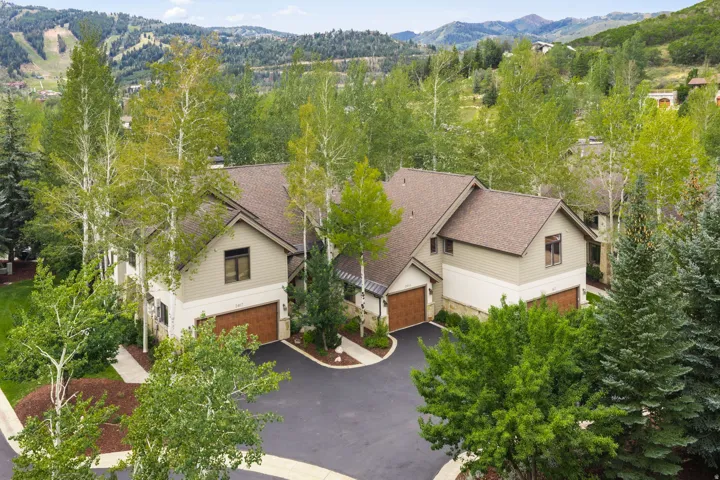Multi-level residence featuring a brown shingle roof, light beige siding, and stone accents