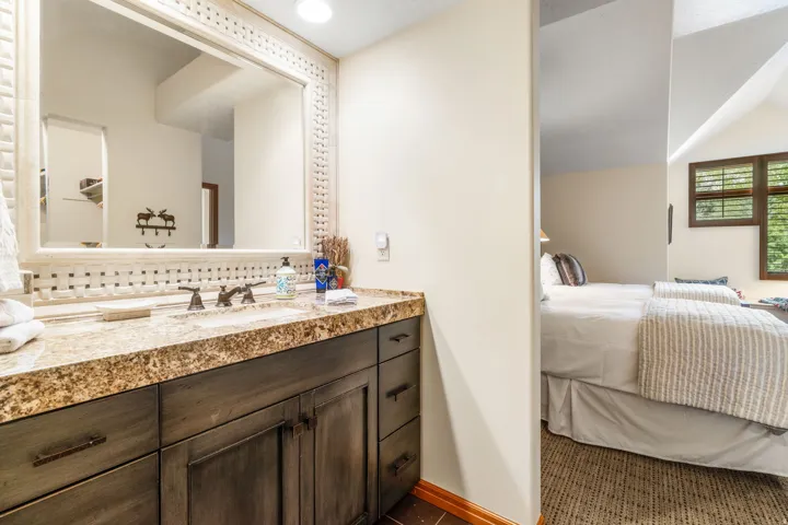 Bathroom vanity with a stone countertop, dual undermount sinks, and a decorative framed mirror
