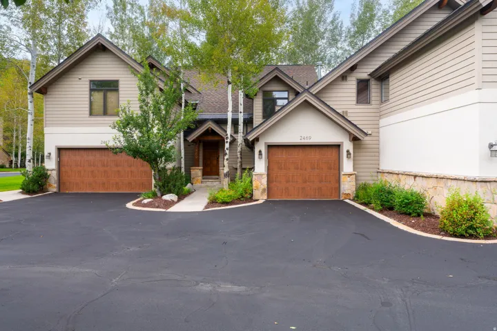 Two-car garage with wood-finish doors, stone accents, and paved driveway