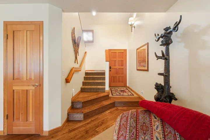 Wood-finish flooring, staircase with carpeted treads, wood paneled doors, and wall-mounted lighting