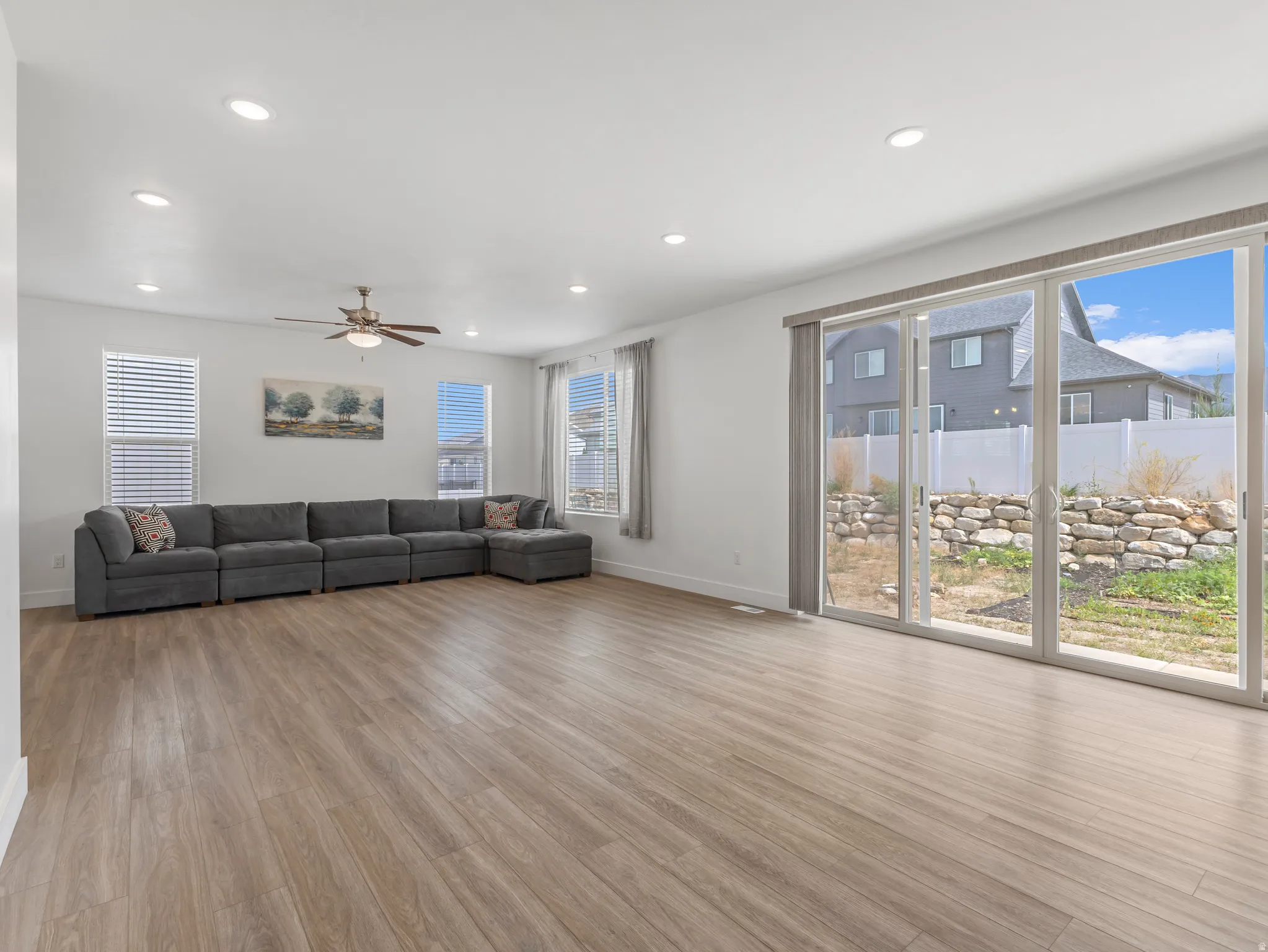 Spacious living area featuring wood-finish flooring, recessed lighting, and a ceiling fan
