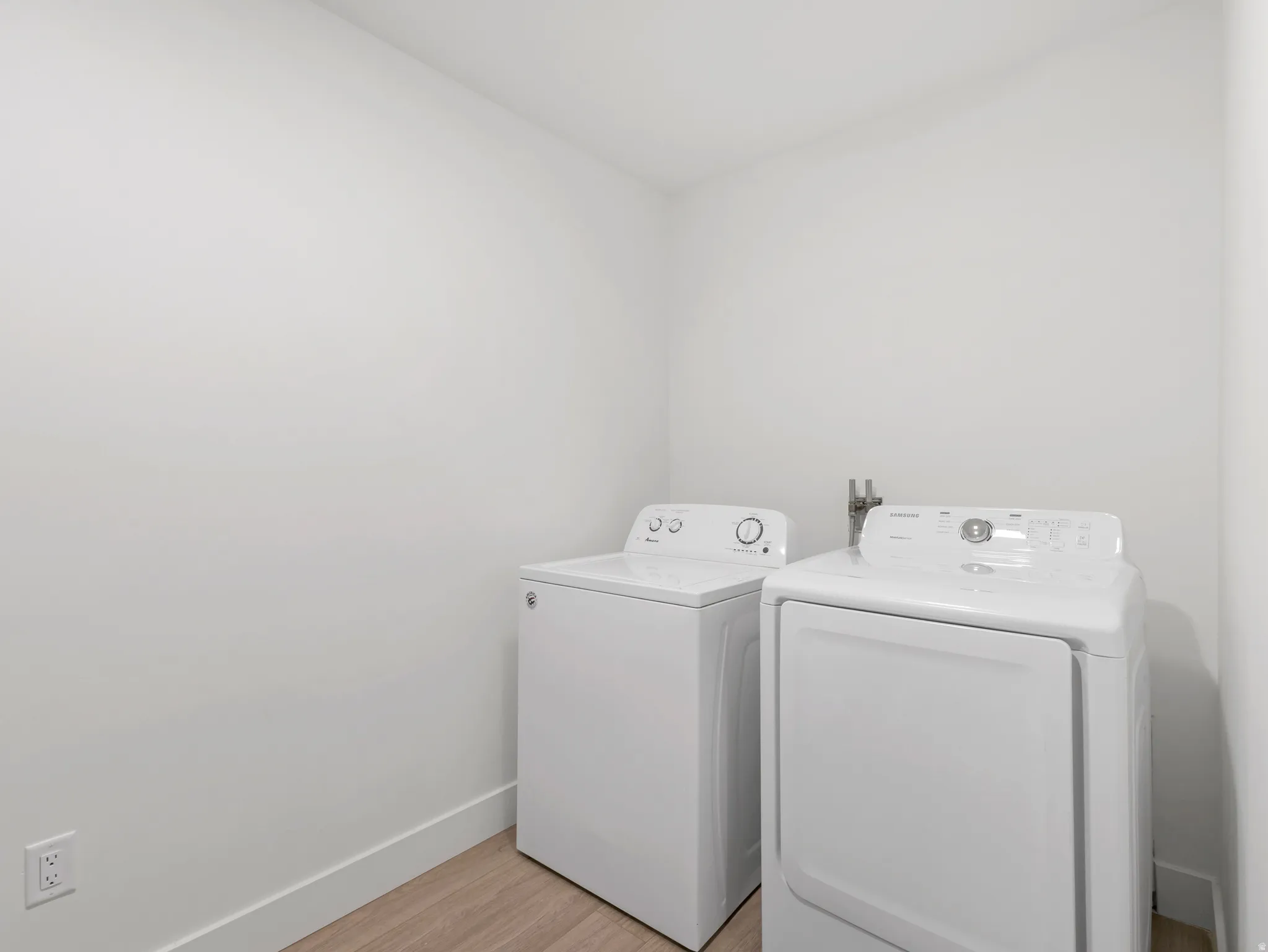 Laundry area with wood-finish flooring and white walls