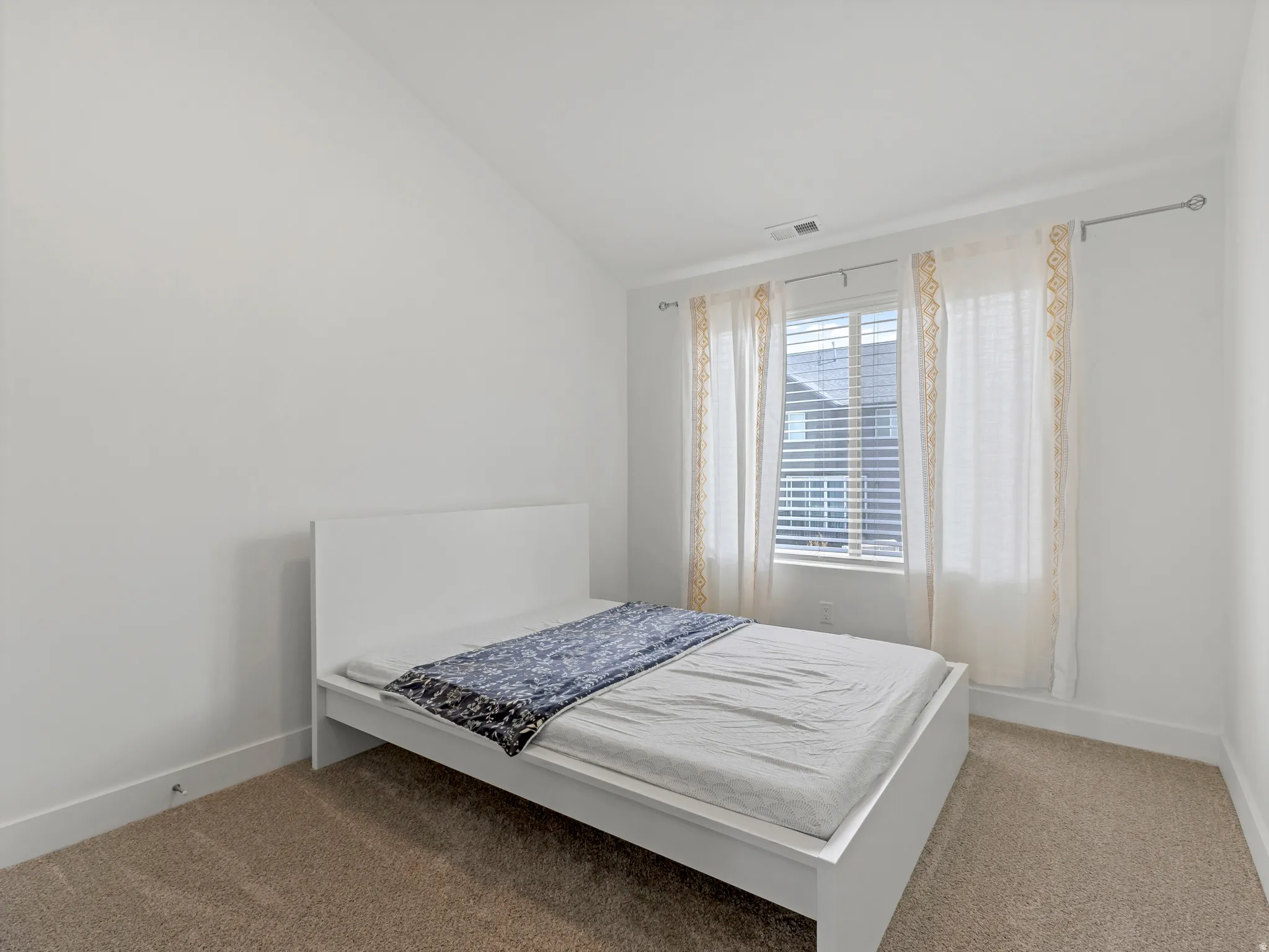 Vaulted ceiling, carpeted flooring, window with blinds, and white walls