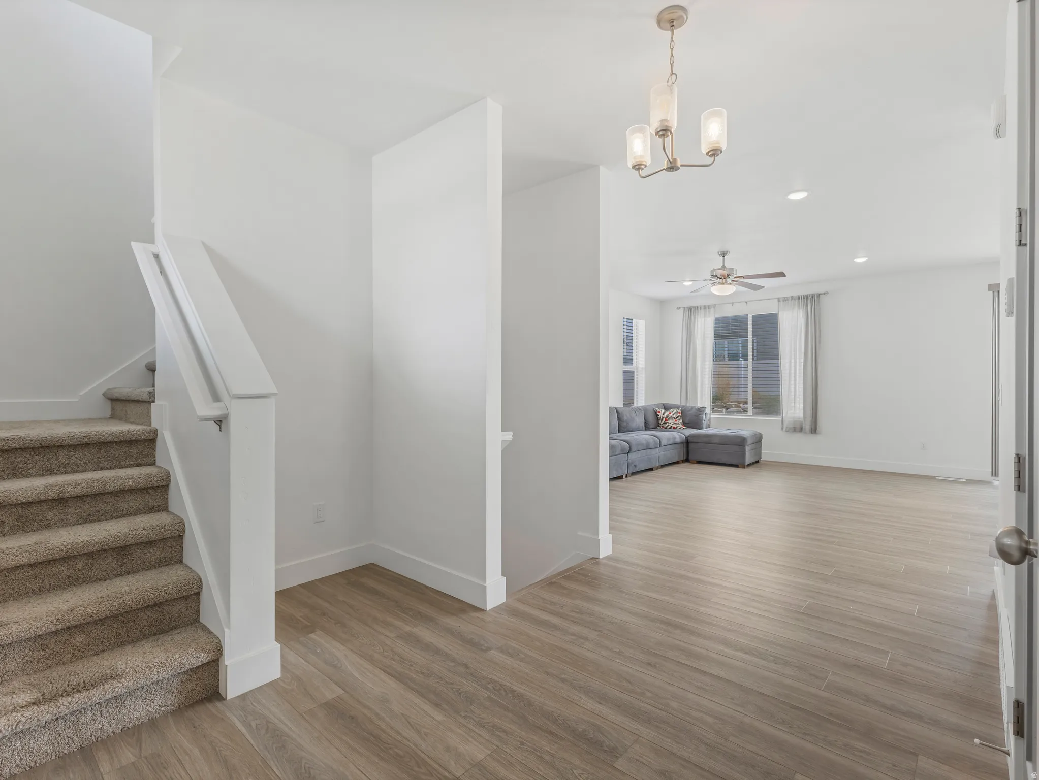 Open-concept living area with wood-finish flooring, ceiling fan, and recessed lighting