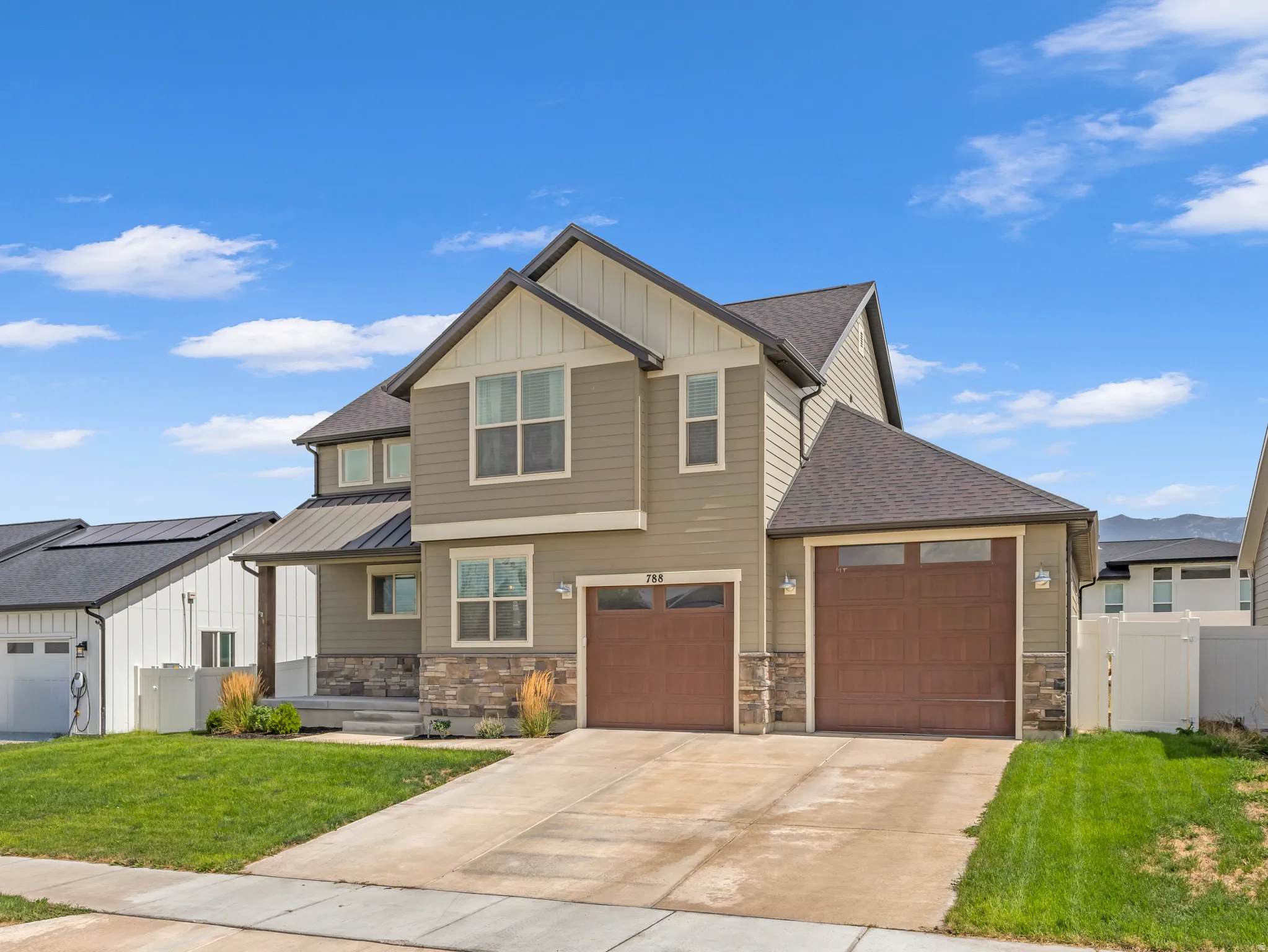 Two-story exterior with a gabled roofline, stone accents, dual garage doors, and a covered porch entry
