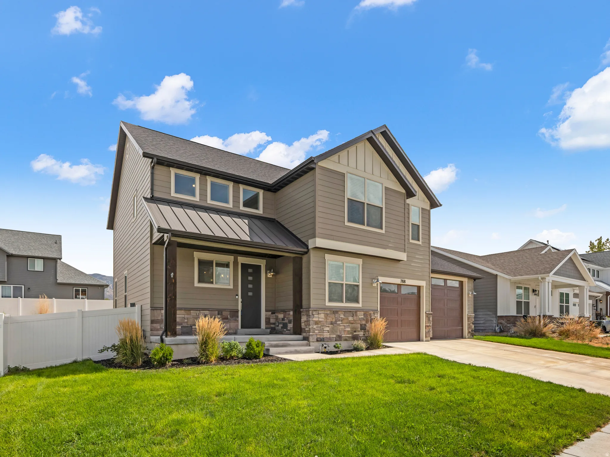 Contemporary exterior with mixed material siding, stone accents, and a metal roof over the entry