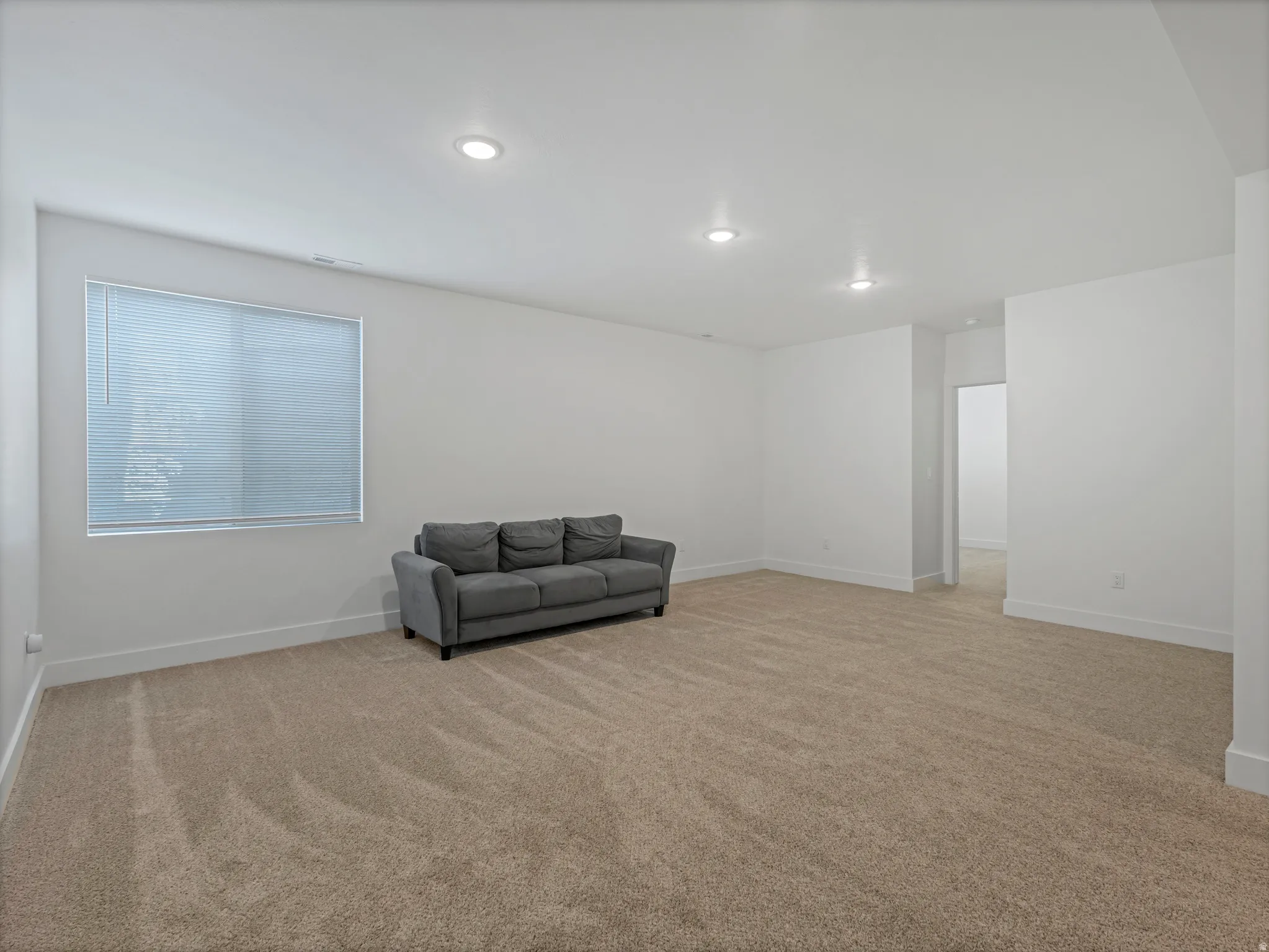 Expansive carpeted room featuring recessed lighting and a window with blinds